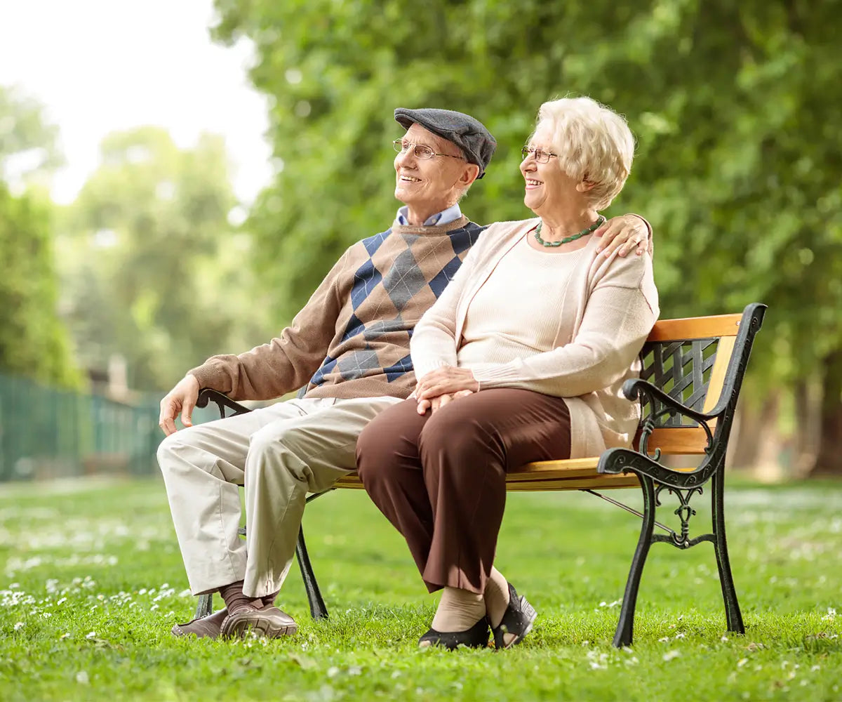 Two old people smiling on a park bench